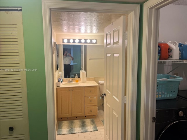 bathroom with vanity, washer / dryer, a textured ceiling, and tile patterned floors