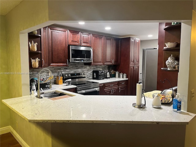 kitchen with kitchen peninsula, light stone countertops, tasteful backsplash, stainless steel appliances, and sink