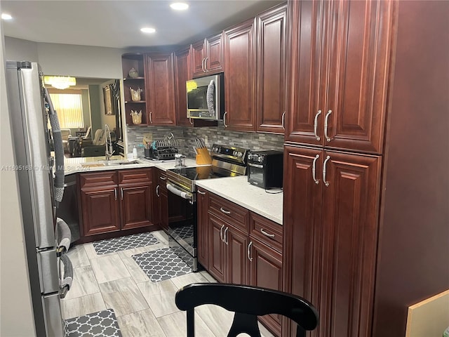 kitchen with decorative backsplash, sink, light stone counters, and stainless steel appliances