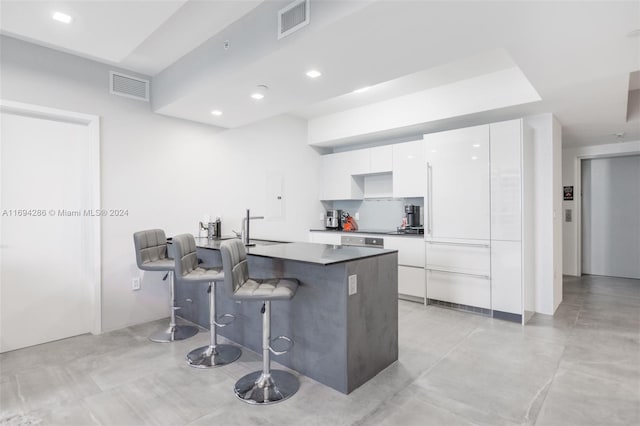 kitchen featuring a breakfast bar, white cabinets, and sink