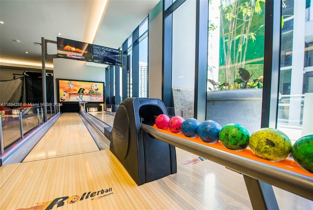 recreation room featuring hardwood / wood-style floors, a bowling alley, and a wall of windows