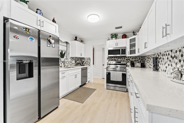 kitchen featuring backsplash, white cabinetry, sink, and appliances with stainless steel finishes