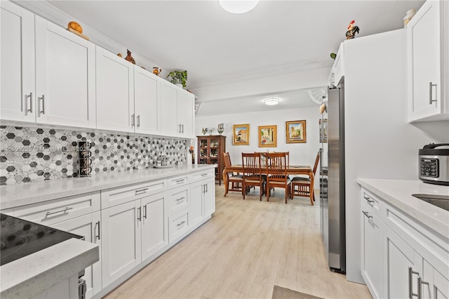 kitchen featuring backsplash, stainless steel refrigerator, white cabinets, and light wood-type flooring