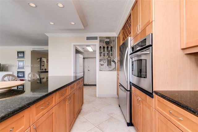 kitchen featuring light tile patterned floors, stainless steel appliances, crown molding, and dark stone countertops