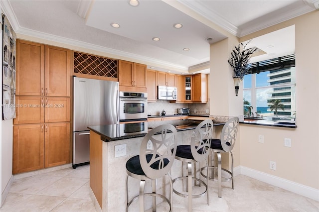 kitchen featuring a breakfast bar, crown molding, kitchen peninsula, and stainless steel appliances