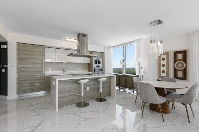 kitchen featuring marble finish floor, island exhaust hood, black electric stovetop, light countertops, and modern cabinets