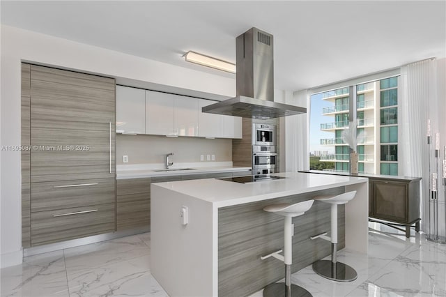 kitchen featuring modern cabinets, marble finish floor, island exhaust hood, black electric cooktop, and a sink