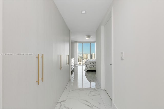 hallway with marble finish floor and a wall of windows