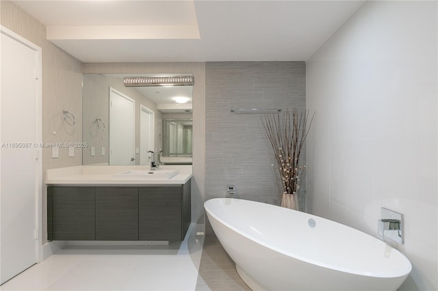 full bathroom featuring vanity, a freestanding tub, and tile walls