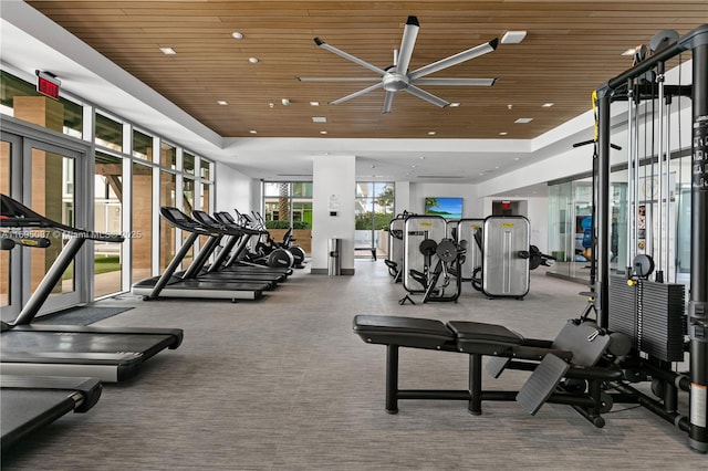 exercise room featuring expansive windows, a raised ceiling, wood ceiling, and recessed lighting