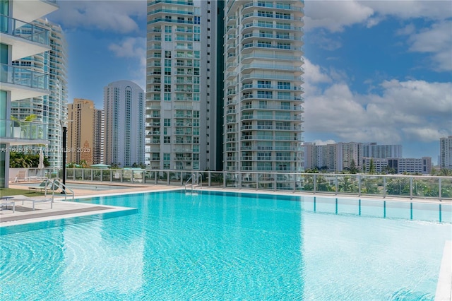 community pool with fence and a city view