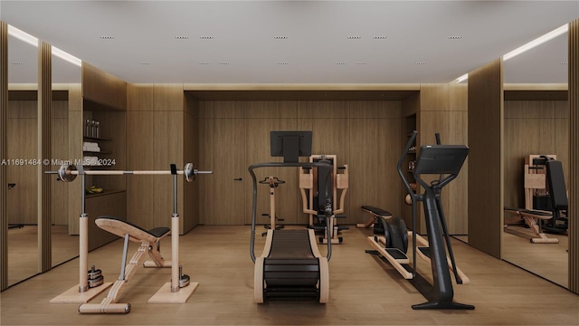 workout area with wood walls and light hardwood / wood-style floors