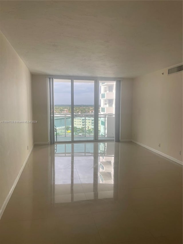 empty room featuring tile patterned floors and expansive windows