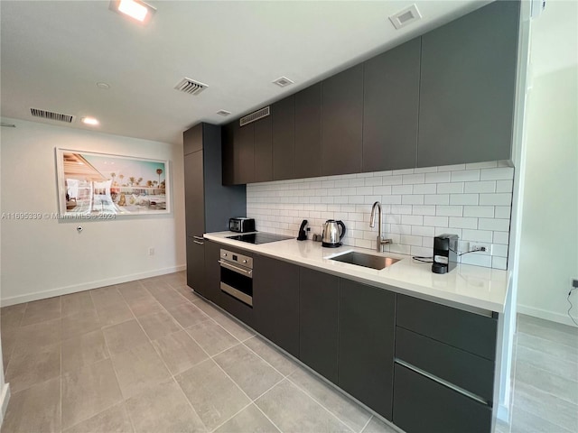 kitchen with decorative backsplash, stainless steel oven, black electric cooktop, sink, and light tile patterned flooring