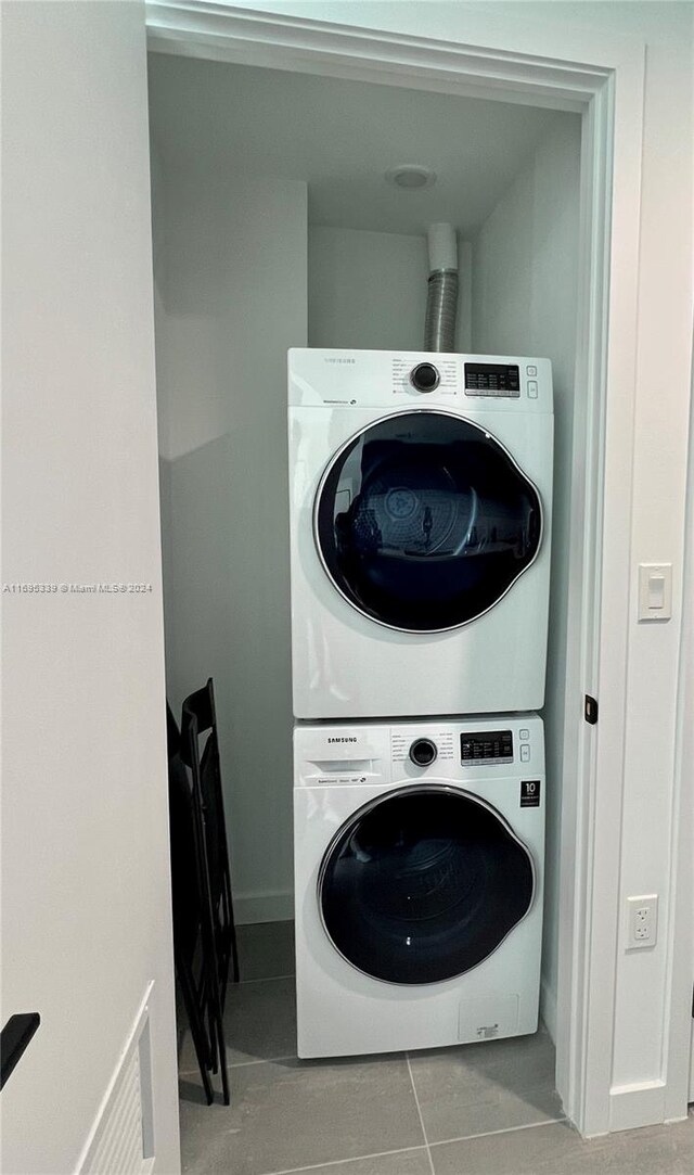 laundry area featuring light tile patterned floors and stacked washer and dryer