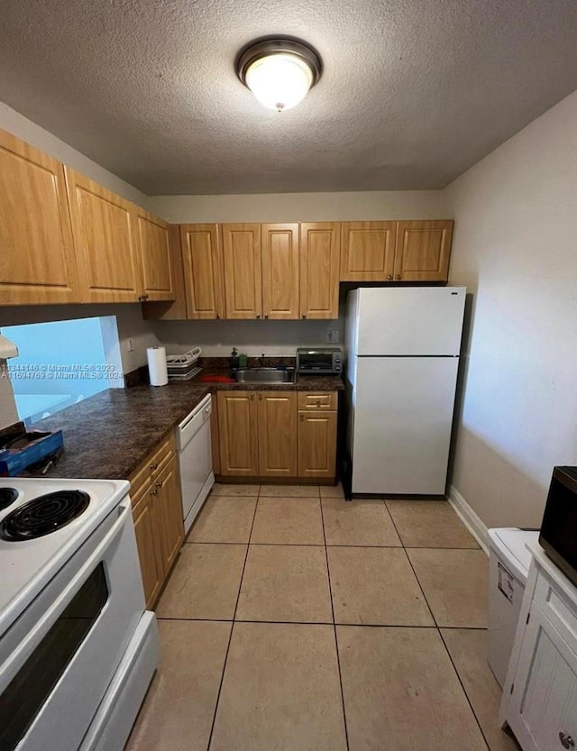 kitchen with a textured ceiling, sink, light tile patterned floors, and white appliances