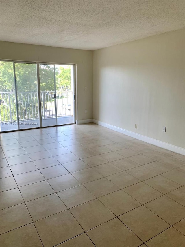 tiled empty room featuring a textured ceiling