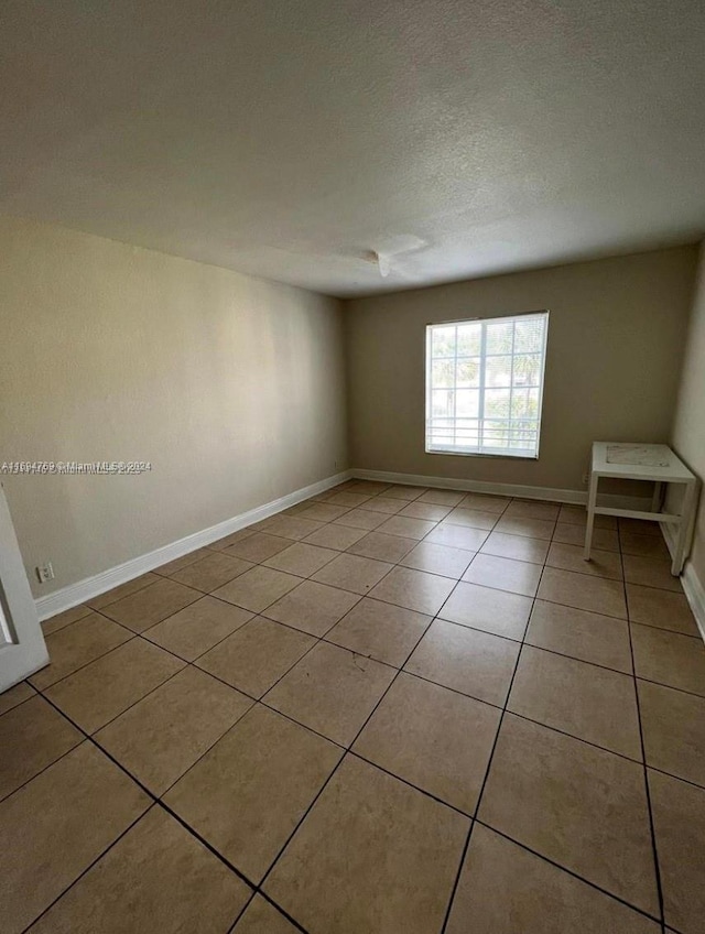 tiled empty room featuring a textured ceiling