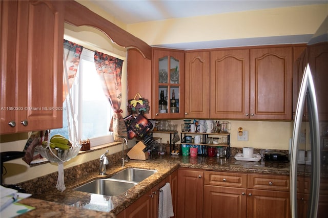 kitchen featuring stainless steel refrigerator, dark stone countertops, and sink