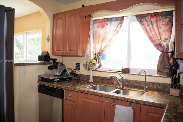 kitchen featuring stainless steel dishwasher, dark stone counters, and sink