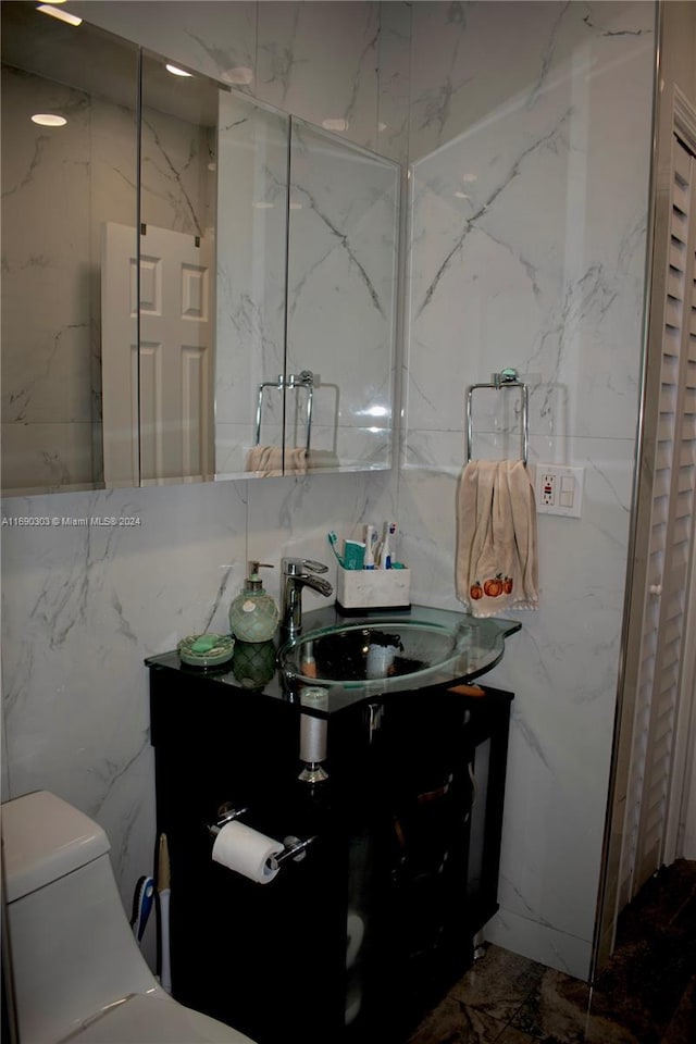 bathroom with vanity, toilet, and tile walls