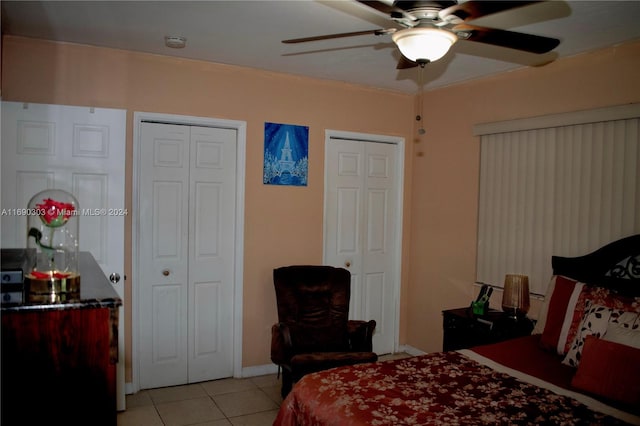 tiled bedroom with two closets and ceiling fan