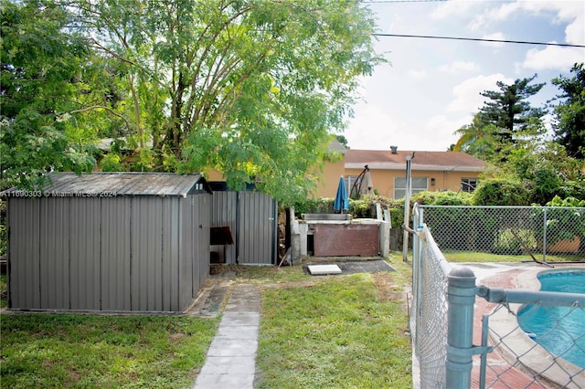 view of yard featuring a storage shed and a pool with hot tub