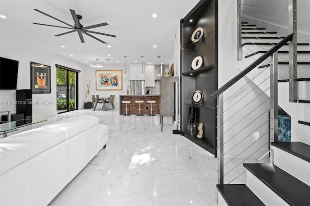 living area featuring stairs, marble finish floor, a ceiling fan, and recessed lighting