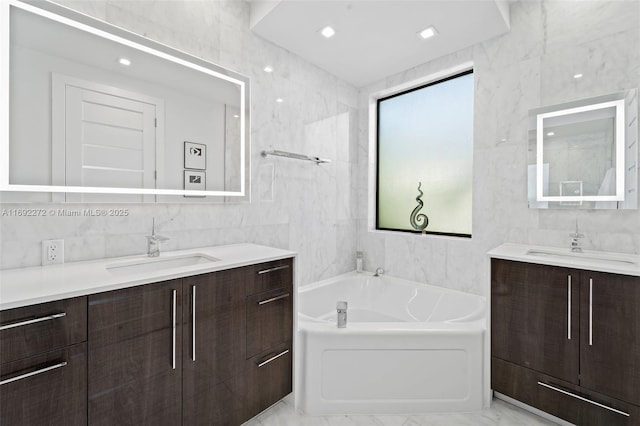 full bath with marble finish floor, two vanities, a sink, and tile walls