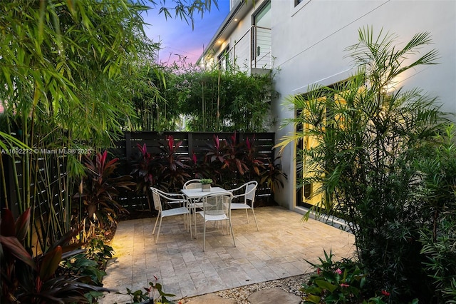 patio terrace at dusk featuring outdoor dining space and a fenced backyard