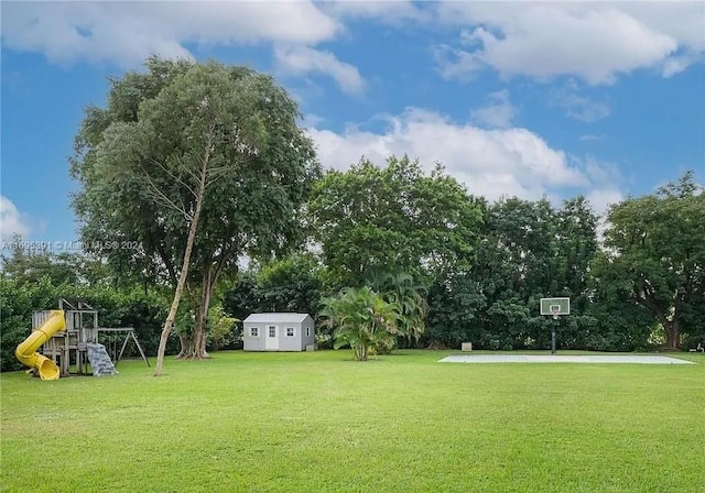 view of yard with basketball court, a playground, and a storage unit