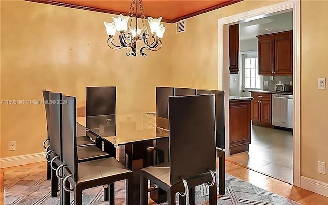 dining space with light wood-type flooring, crown molding, and a notable chandelier