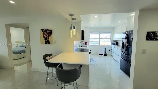 kitchen featuring a breakfast bar, white cabinets, decorative light fixtures, black fridge with ice dispenser, and kitchen peninsula