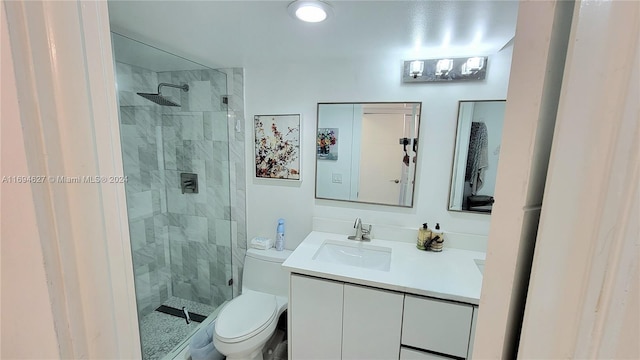 bathroom with a tile shower, vanity, and toilet