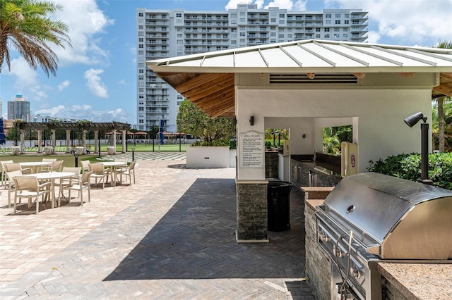 view of patio with an outdoor kitchen, a pergola, and a grill