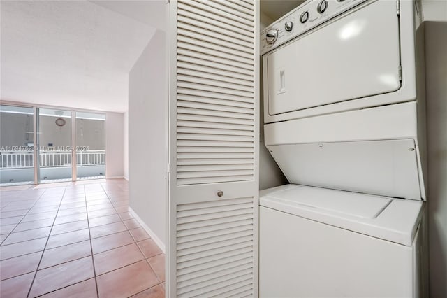 laundry room featuring light tile patterned floors and stacked washing maching and dryer