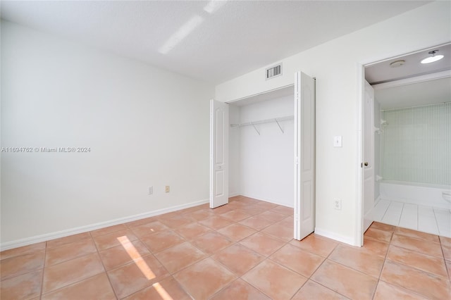 unfurnished bedroom featuring light tile patterned floors, a textured ceiling, and a closet