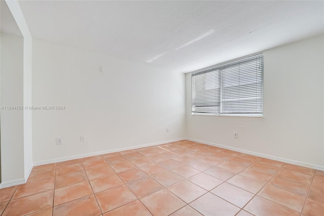 empty room featuring light tile patterned floors and a textured ceiling