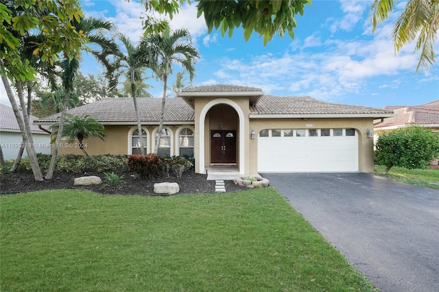 mediterranean / spanish-style home featuring a front yard and a garage