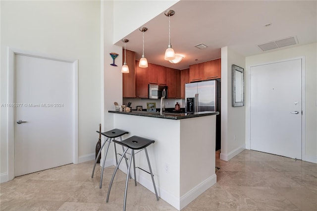 kitchen with kitchen peninsula, appliances with stainless steel finishes, a breakfast bar, and decorative light fixtures