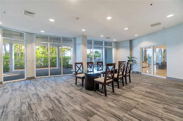 dining space with plenty of natural light, a wall of windows, and wood-type flooring