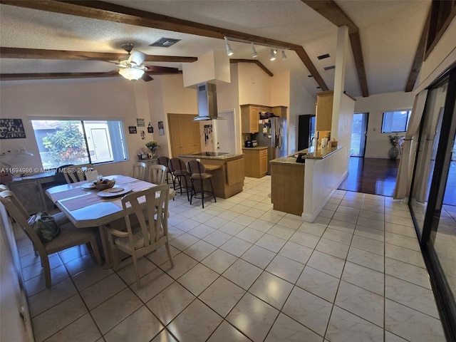 kitchen featuring wall chimney range hood, vaulted ceiling with beams, stainless steel refrigerator with ice dispenser, a textured ceiling, and kitchen peninsula