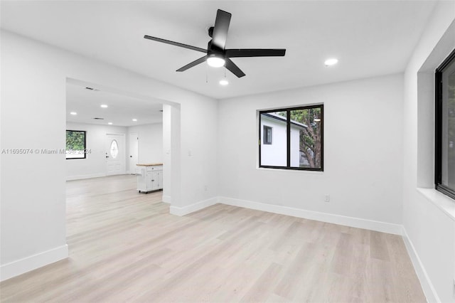 empty room with ceiling fan and light hardwood / wood-style flooring