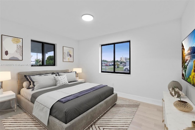 bedroom with light hardwood / wood-style floors and multiple windows