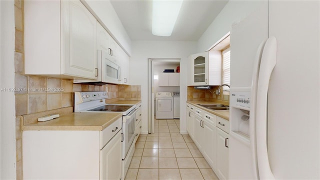 kitchen with white cabinetry, sink, washing machine and dryer, backsplash, and white appliances