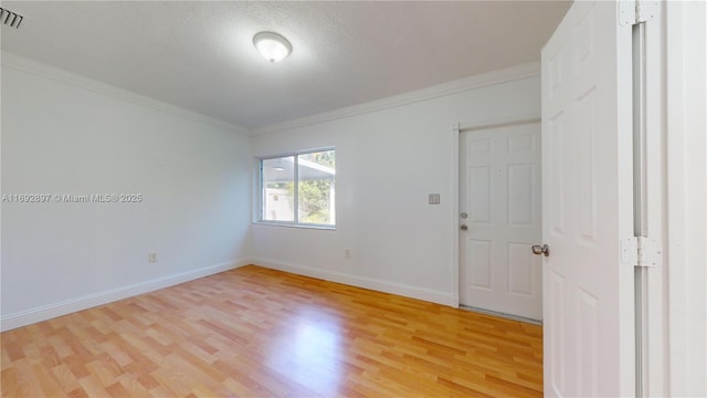 spare room featuring crown molding, light hardwood / wood-style floors, and a textured ceiling