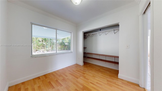 unfurnished bedroom featuring hardwood / wood-style flooring, ornamental molding, and a closet