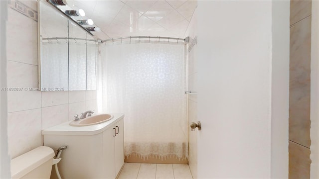 full bathroom with vanity, tile patterned floors, toilet, shower / bath combo with shower curtain, and tile walls