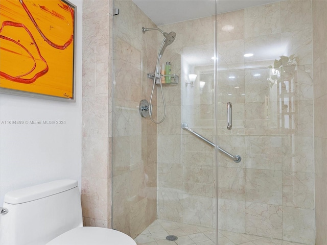 bathroom featuring toilet and a shower with shower door