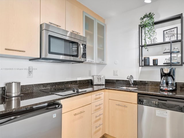 kitchen featuring dark stone counters, light brown cabinets, stainless steel appliances, and sink